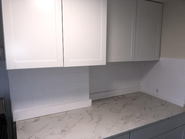 room details with white cabinets and light stone countertops