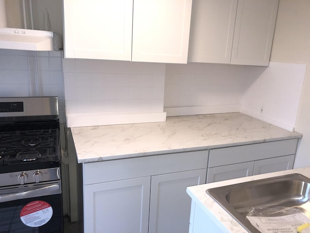 kitchen with gas range, sink, tasteful backsplash, and white cabinetry