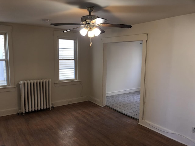 empty room with ceiling fan, radiator heating unit, and dark hardwood / wood-style floors