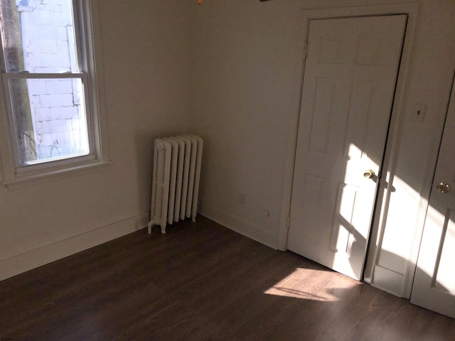 spare room with radiator heating unit and dark hardwood / wood-style floors