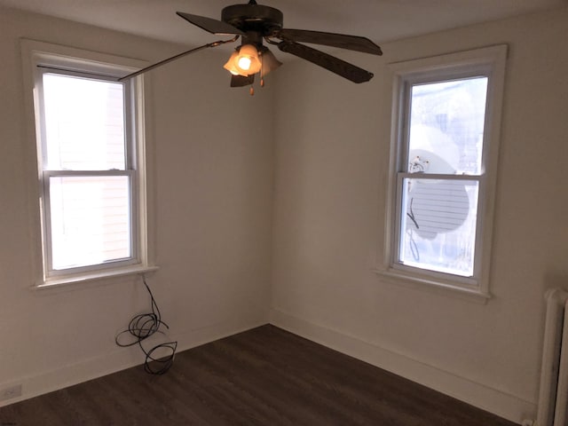 unfurnished room featuring dark hardwood / wood-style flooring, ceiling fan, and radiator heating unit