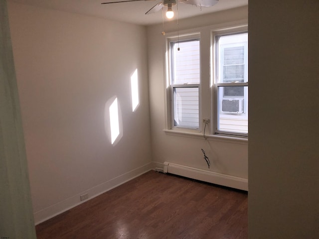 spare room featuring ceiling fan, baseboard heating, and dark hardwood / wood-style floors