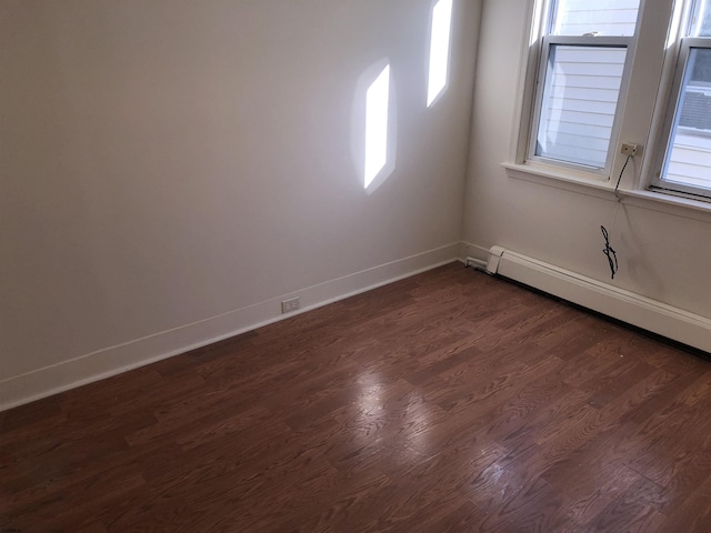 spare room with baseboard heating and dark hardwood / wood-style flooring