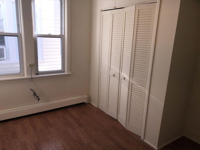 unfurnished bedroom featuring a closet, a baseboard radiator, and dark hardwood / wood-style flooring