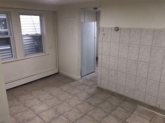 unfurnished room featuring tile walls, a baseboard radiator, and light tile patterned floors