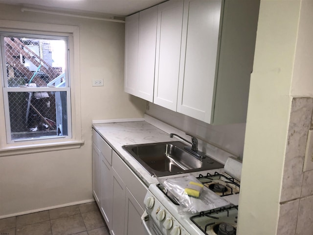 kitchen featuring sink, white cabinets, dark tile patterned flooring, and white gas range oven