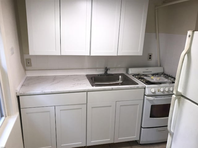 kitchen with white appliances, light stone countertops, tasteful backsplash, white cabinetry, and sink