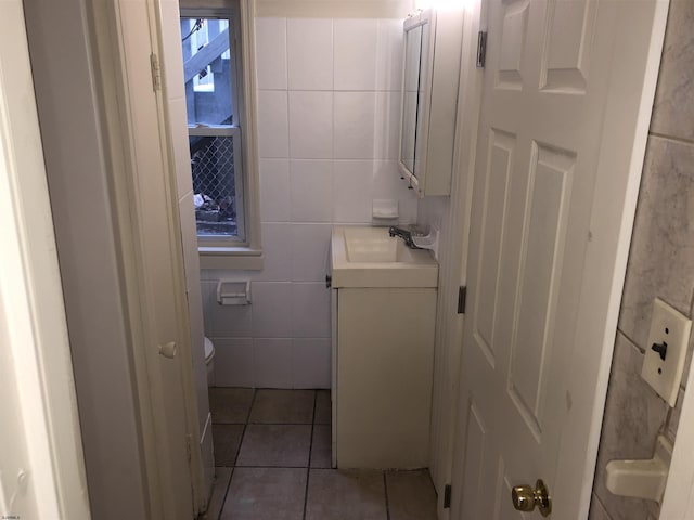 bathroom with toilet, tile patterned floors, tile walls, and vanity