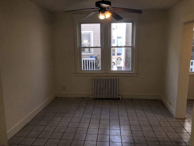 unfurnished room featuring ceiling fan, light tile patterned flooring, and radiator