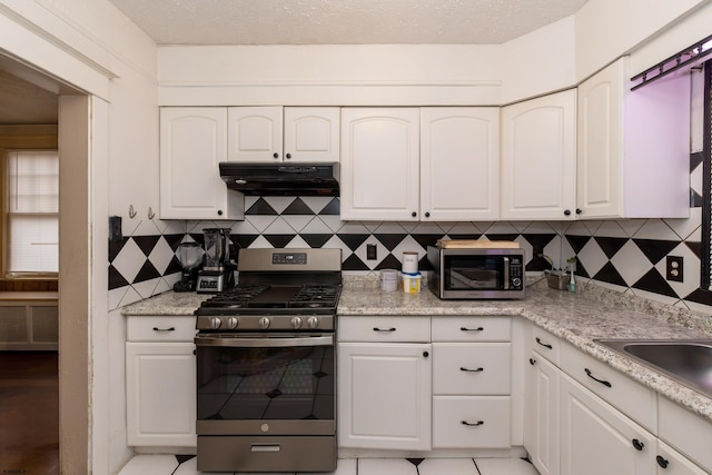 kitchen featuring light tile patterned floors, appliances with stainless steel finishes, backsplash, and white cabinetry