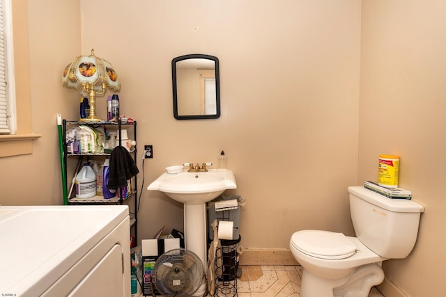 bathroom featuring toilet, tile patterned floors, and washer / dryer