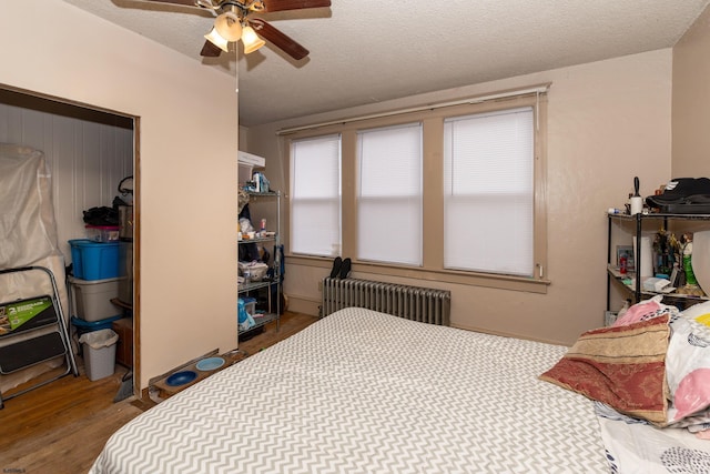 bedroom with radiator, ceiling fan, a textured ceiling, and wood-type flooring