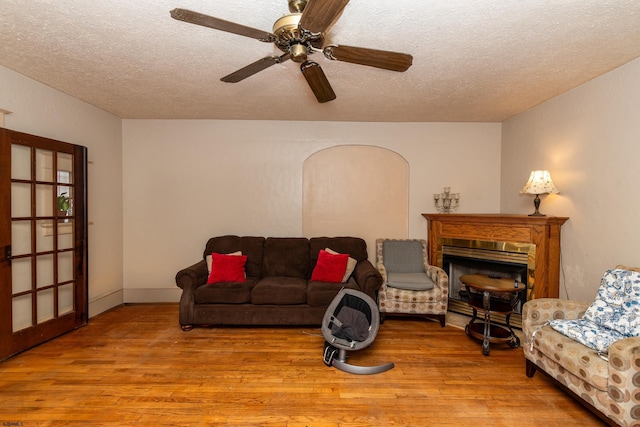 living room with light hardwood / wood-style floors, a textured ceiling, and ceiling fan