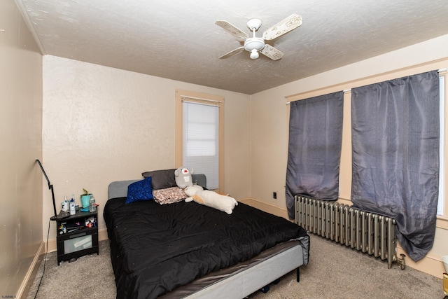 bedroom with ceiling fan, a textured ceiling, radiator, and light carpet