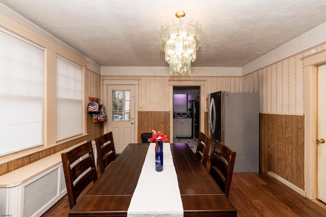 dining space featuring wooden walls, a chandelier, and a textured ceiling