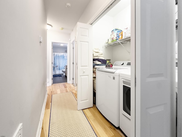 clothes washing area with washer and clothes dryer and light hardwood / wood-style floors