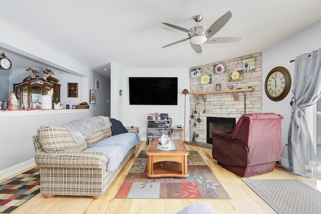 living room with ceiling fan, a fireplace, and light hardwood / wood-style floors