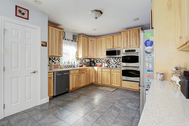 kitchen with backsplash, light brown cabinetry, appliances with stainless steel finishes, and sink