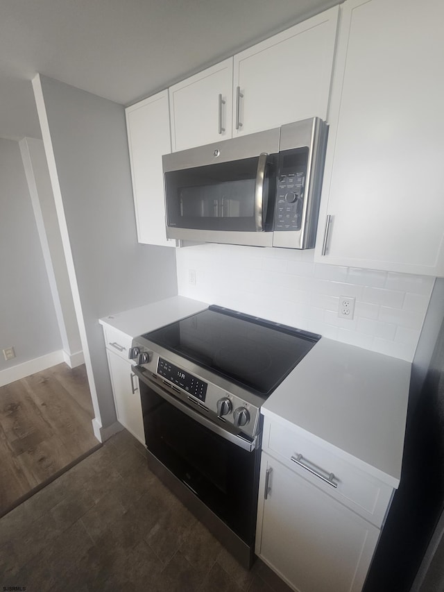 kitchen featuring white cabinets, appliances with stainless steel finishes, and dark hardwood / wood-style flooring