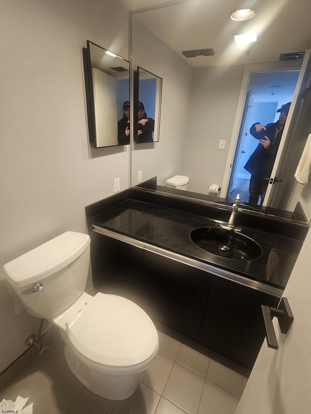 bathroom with toilet, vanity, and tile patterned flooring