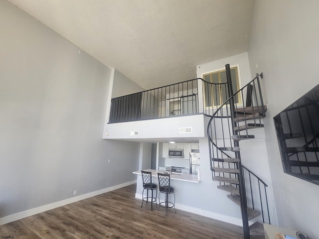 stairs featuring a towering ceiling, a textured ceiling, and hardwood / wood-style floors