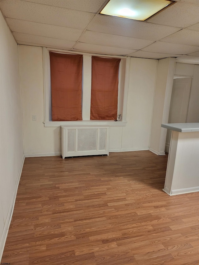 unfurnished room featuring radiator, a paneled ceiling, and light hardwood / wood-style floors