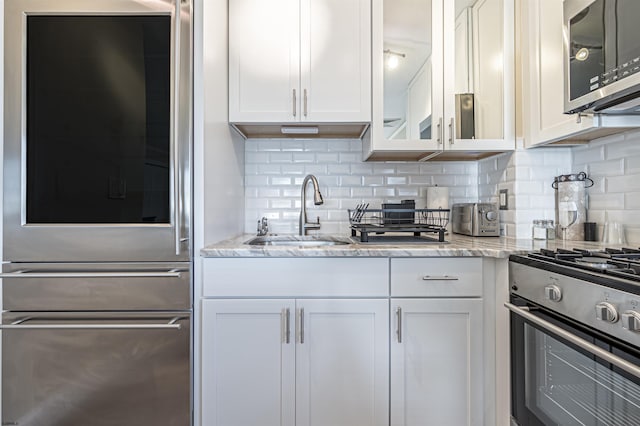 kitchen with sink, light stone counters, stainless steel appliances, and white cabinetry