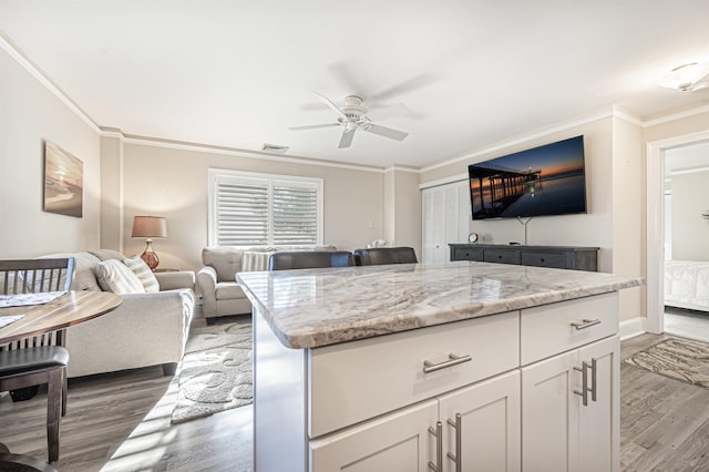 kitchen featuring light stone countertops, white cabinetry, dark hardwood / wood-style floors, and ornamental molding