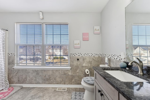 bathroom featuring tile patterned floors, tile walls, toilet, and vanity