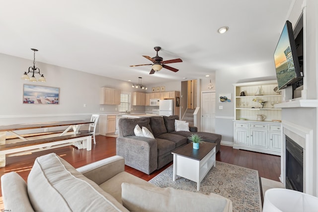 living room with ceiling fan with notable chandelier and hardwood / wood-style floors