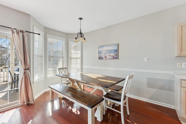 dining area with a healthy amount of sunlight, dark hardwood / wood-style floors, and an inviting chandelier