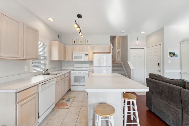 kitchen with pendant lighting, a breakfast bar, sink, white appliances, and light tile patterned floors