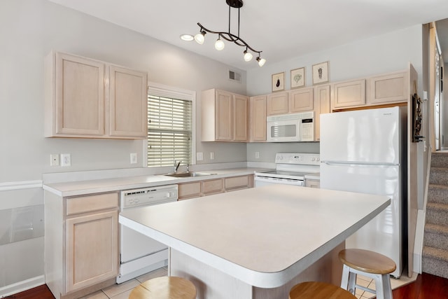 kitchen featuring a kitchen island, sink, white appliances, hanging light fixtures, and a breakfast bar area