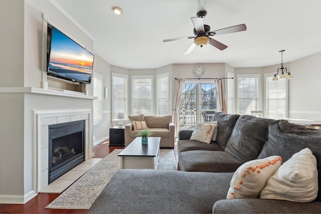 living room with a tile fireplace, ceiling fan with notable chandelier, and light hardwood / wood-style floors