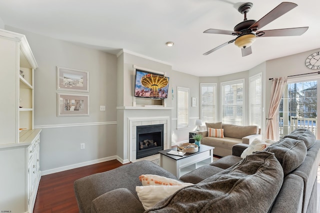 living room with dark hardwood / wood-style floors, a tiled fireplace, and ceiling fan