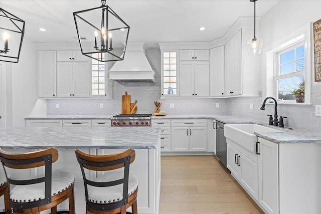 kitchen featuring stainless steel appliances, custom exhaust hood, white cabinets, and hanging light fixtures