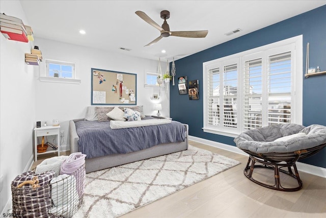 bedroom with ceiling fan, multiple windows, and hardwood / wood-style floors