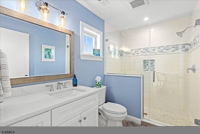 bathroom featuring a shower with shower door, vanity, and toilet