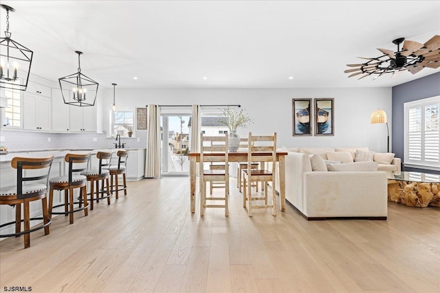 living room featuring light wood-type flooring, a healthy amount of sunlight, a notable chandelier, and sink