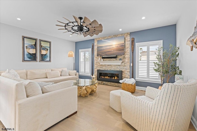 living room featuring ceiling fan, a fireplace, and light hardwood / wood-style flooring