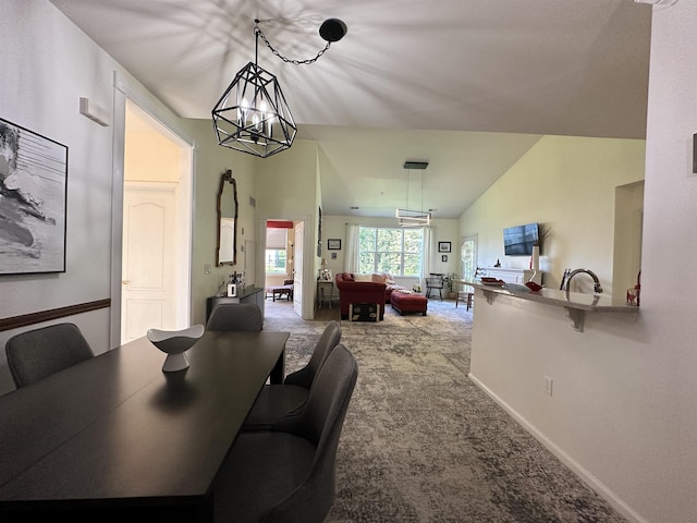 dining room with carpet flooring, lofted ceiling, and a notable chandelier