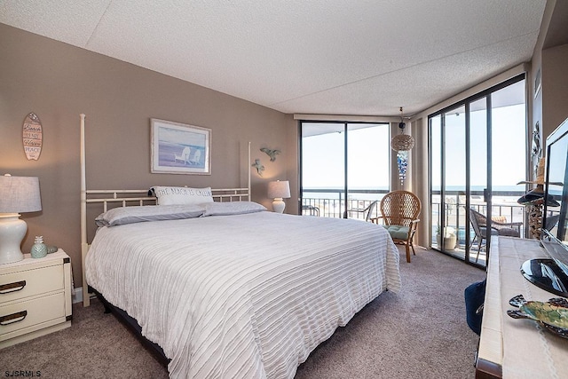 carpeted bedroom featuring a textured ceiling, access to exterior, a wall of windows, and a water view