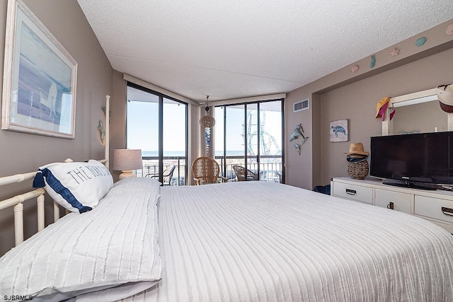 bedroom featuring a textured ceiling, floor to ceiling windows, and access to outside