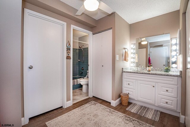 full bathroom featuring toilet, vanity, tiled shower / bath, hardwood / wood-style floors, and a textured ceiling