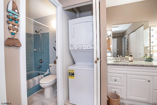 full bathroom featuring toilet, stacked washer / drying machine, tiled shower / bath combo, tile patterned floors, and vanity