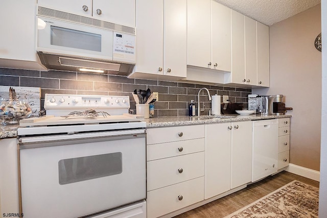 kitchen with hardwood / wood-style floors, sink, white appliances, white cabinetry, and light stone countertops