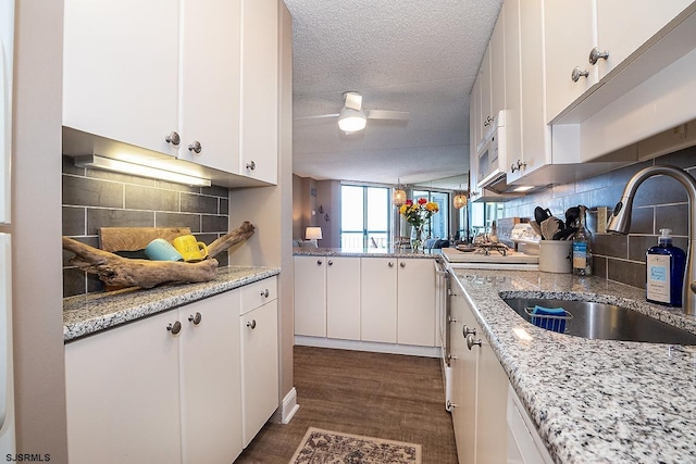 kitchen with a textured ceiling, white cabinetry, tasteful backsplash, and sink