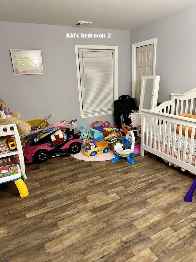 bedroom featuring hardwood / wood-style flooring and a crib