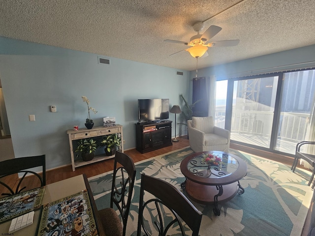 living room with ceiling fan, a textured ceiling, and hardwood / wood-style floors