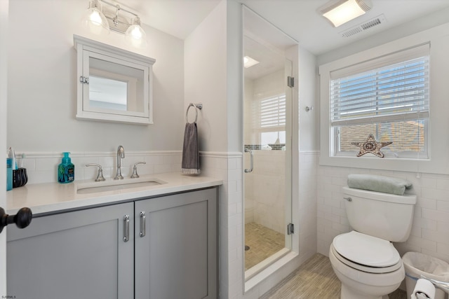 bathroom with toilet, tile walls, walk in shower, and vanity